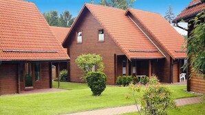 A row of wooden cabins with red-tiled roofs, a well-maintained lawn, and a gravel path. - Ferienhaus in Hasselfelde (Oberharz am Brocken)