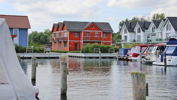 A waterfront property with a red house, a blue house, and a white house. - Ferienwohnung in Plau am See (Plau am See)