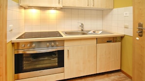 A kitchen with a stove, oven, sink, and wooden cabinets. - Ferienwohnung in Plau am See (Plau am See)