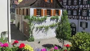 A traditional half-timbered house with wooden shutters, a sloped roof, and a small garden with colorful flowers. - Apartment Bears, Meersburg (Meersburg)