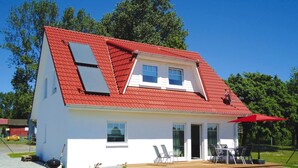 A modern house with a red roof, a balcony, and a patio area with outdoor seating. - Starfish Holiday Home in Rerik Near Beach (Rerik)