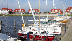 A marina with several sailboats docked, wooden walkways, and red-roofed buildings in the background. - Starfish Holiday Home in Rerik Near Beach (Rerik)