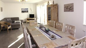 A dining area with a wooden table, chairs, and a television in the background. - Starfish Holiday Home in Rerik Near Beach (Rerik)