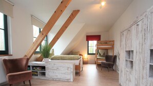 A loft-style bedroom with a sloped ceiling, a bunk bed, a desk with a chair, a radiator, and a large wardrobe. - Doppelhaushalfte, Glave (Dobbin-Linstow)