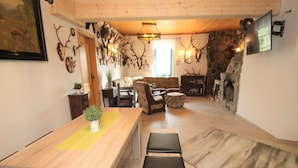 A spacious living area with a wooden dining table, a stone fireplace, and a stone wall. - Doppelhaushalfte, Glave (Dobbin-Linstow)