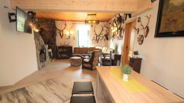 A cozy living room with a stone fireplace, a wooden dining table, and a sofa. - Doppelhaushalfte, Glave (Dobbin-Linstow)