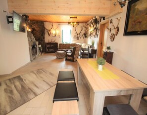 Una sala de estar acogedora con chimenea de piedra, una mesa de comedor de madera y un sofá.