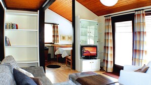 Ein gemütliches Wohnzimmer mit einer Couch, einem Fernseher und einem Essbereich mit Tisch und Stühlen.