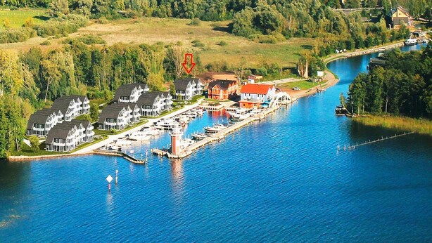 A marina with docked boats, a small pier, and a row of houses with red roofs. - Appartement Hafenflair am Plauer See (Plau am See)