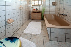 Un baño con bañera, lavamanos, inodoro y ducha.