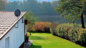 Ein Haus mit Satellitenschüssel, Rasen und einem See im Hintergrund.