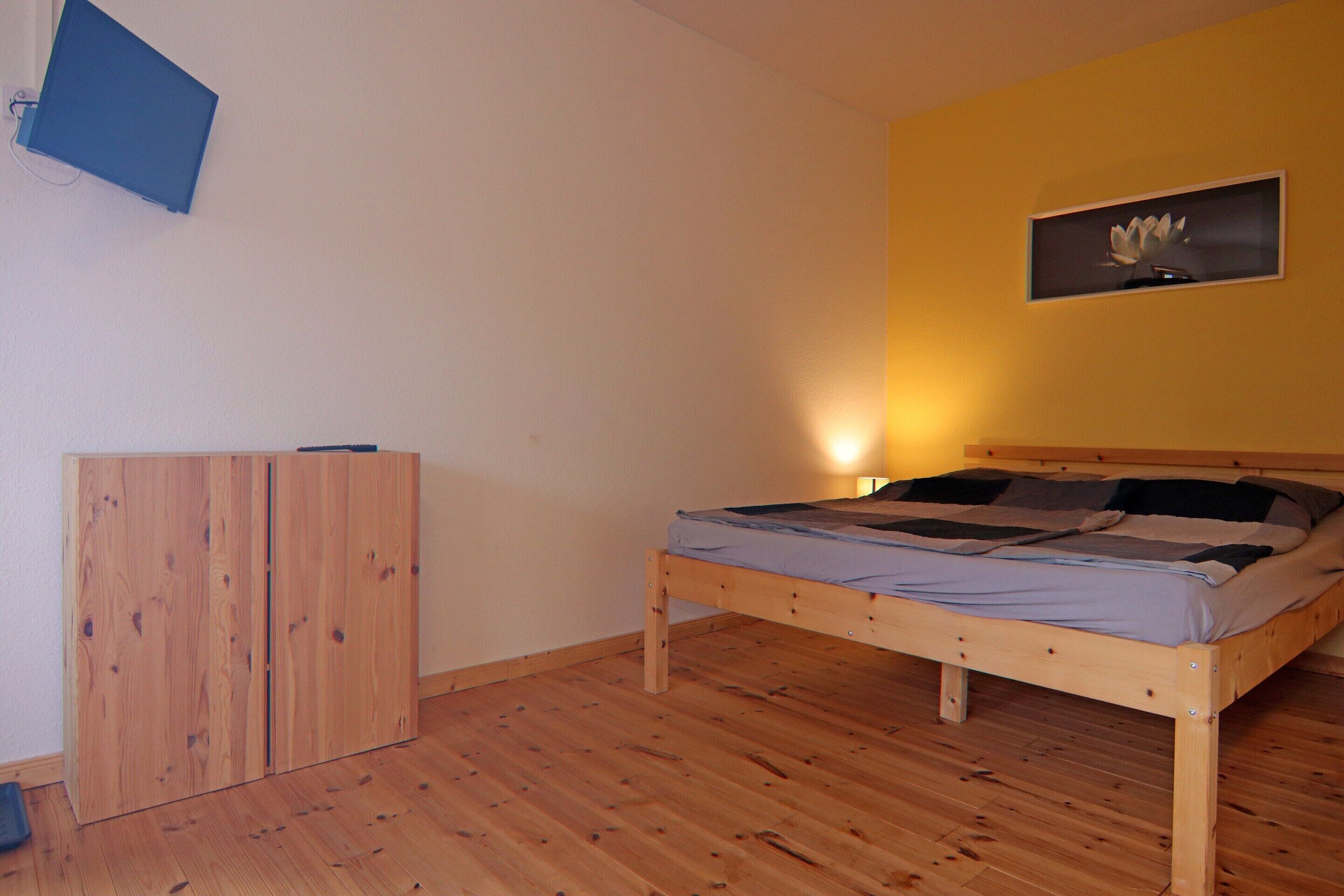 A bedroom with a wooden bed, a wardrobe, and a wall-mounted picture.