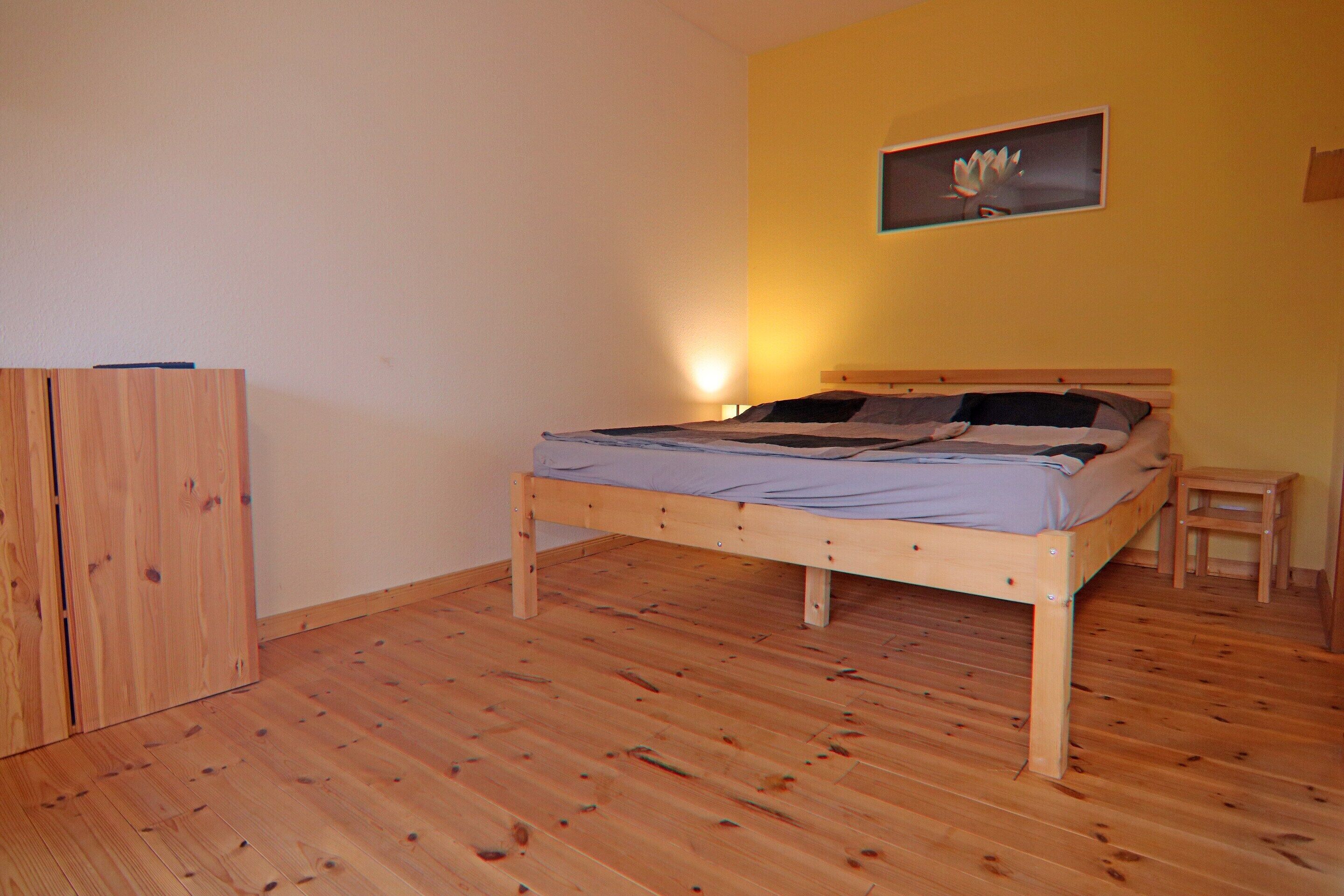 A bedroom with a wooden bed, a nightstand, and a wardrobe.
