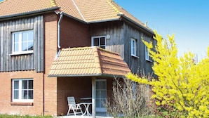 A two-story house with a brick exterior, a tiled roof, and a small porch with a table and chairs. - Ferienanlage Petersdorf auf Fehmarn-petersdorf (Fehmarn)
