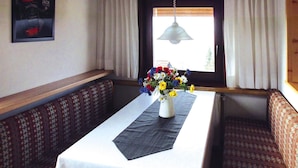 A dining area with a table set for two, a vase of flowers, and patterned seating. - Feriendorf Ofingen, Bad Durrheim (Bad Duerrheim)