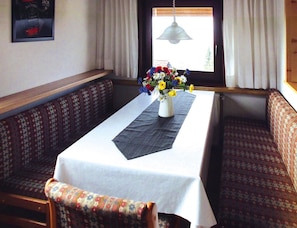 A dining area with a table set for two, a vase of flowers, and patterned seating. - Feriendorf Ofingen, Bad Durrheim (Bad Duerrheim)