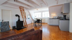 A spacious loft with a kitchen, dining area, and a loft bed. - Ferienwohnungen am Flacher See, Klocksin (Klocksin)