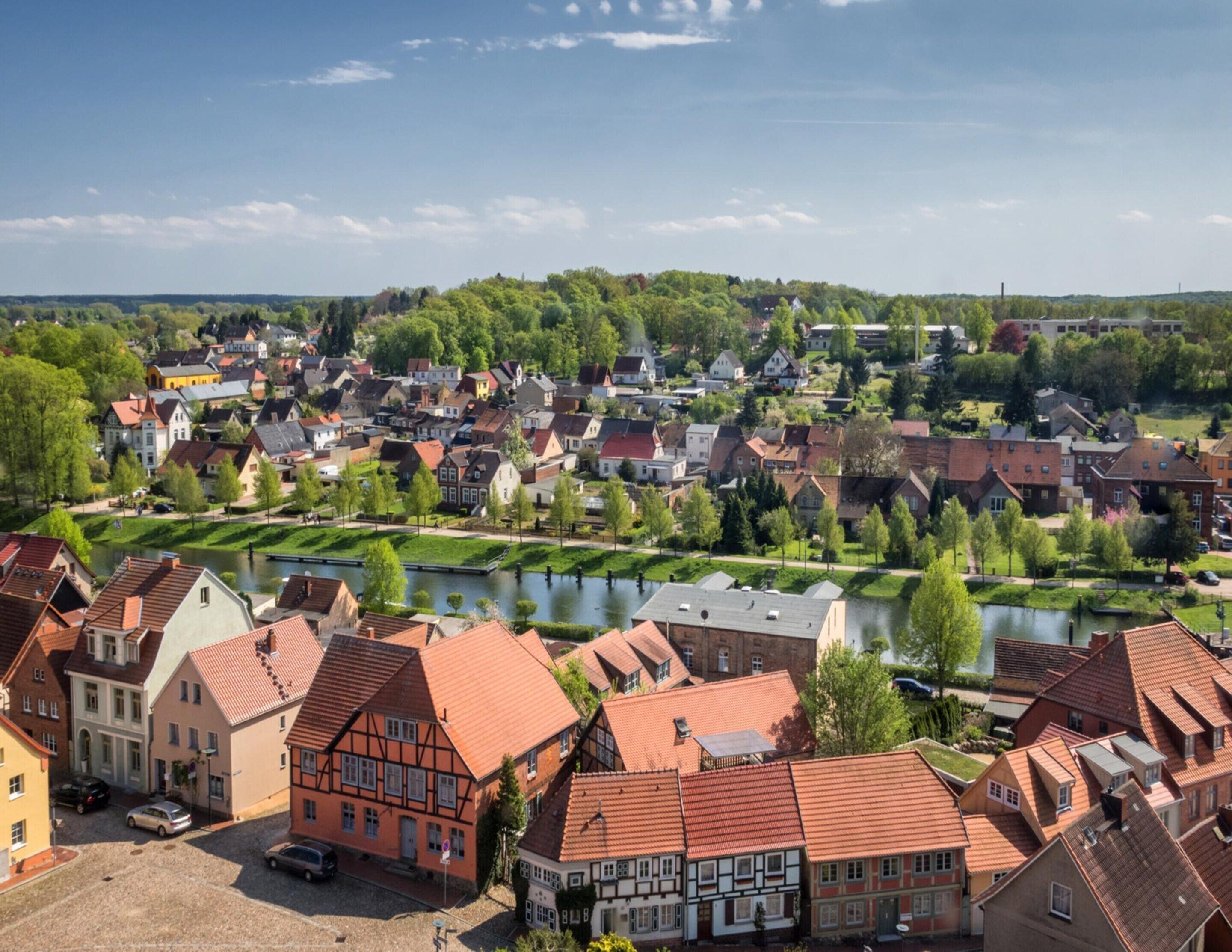 Un pueblo con arquitectura europea tradicional, un río y una combinación de edificios residenciales y comerciales.