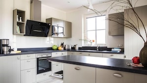 A modern kitchen with a central island, built-in appliances, and ample storage. - Ferienhaus, Fuhlendorf (Fuhlendorf)