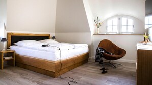 A bedroom with a wooden bed, a chair, a desk, and a window. - Ferienhaus, Fuhlendorf (Fuhlendorf)