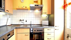 Keittiössä on puiset kaapit, ruostumattomasta teräksestä valmistettu uuni, mikroaaltouuni ja seinällä oleva kello.