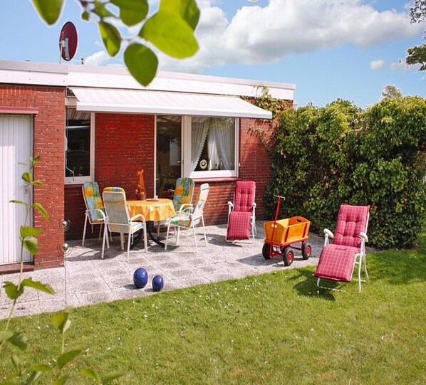 A patio with outdoor furniture, a table, and a red chair. - Bungalow Klonsnack in Dornumersiel (Dornum)