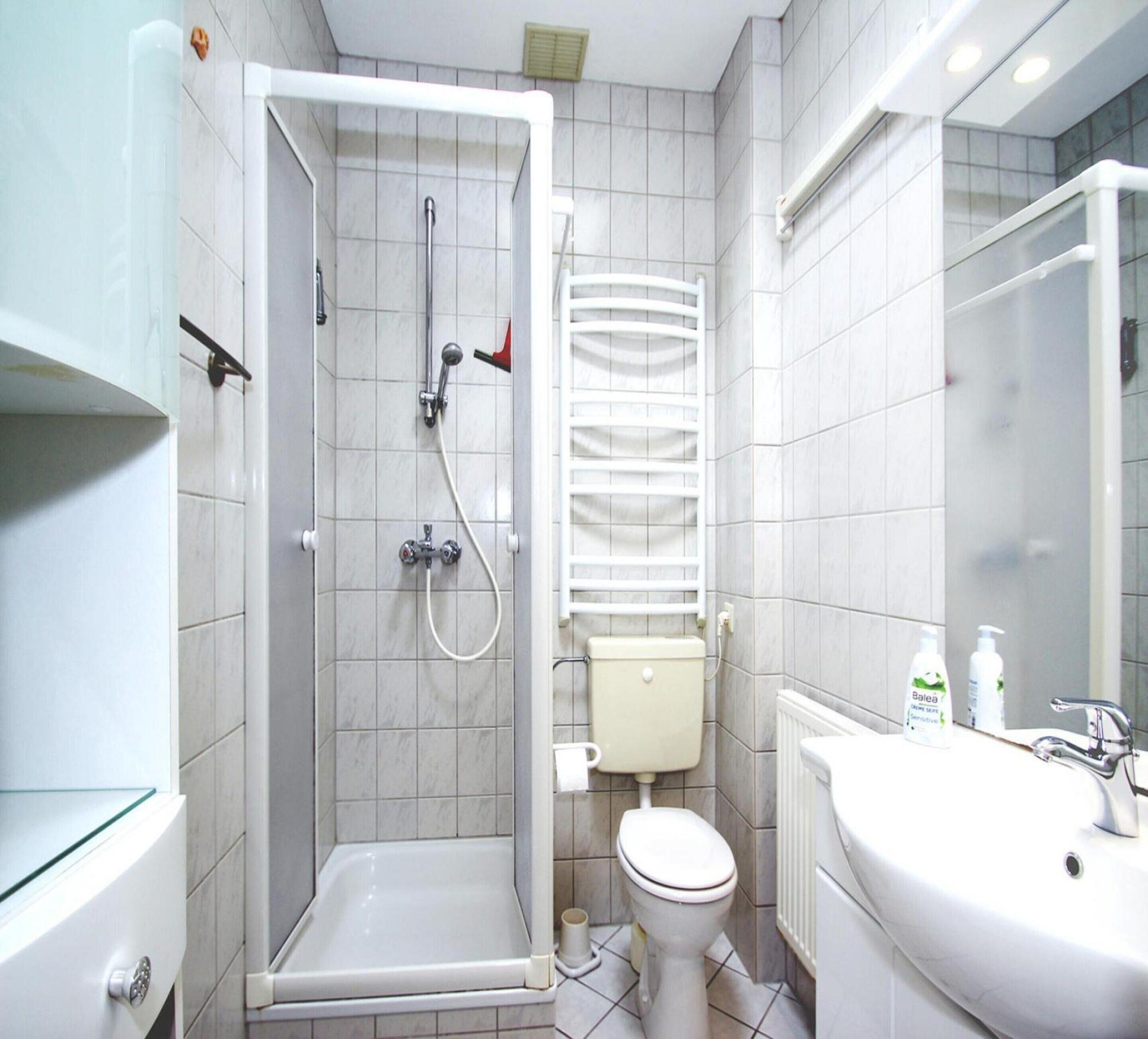 A modern bathroom with a glass-enclosed shower, a toilet, and a sink.