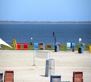 Une plage avec des boîtes aux lettres numérotées et une zone délimitée par un filet au premier plan.