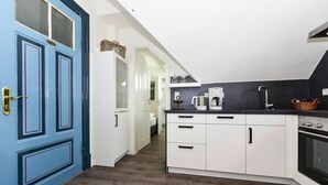 A modern kitchen with white cabinets, a black countertop, and a built-in oven. - Appartements, Wyk auf Fohr (Wyk auf Foehr)