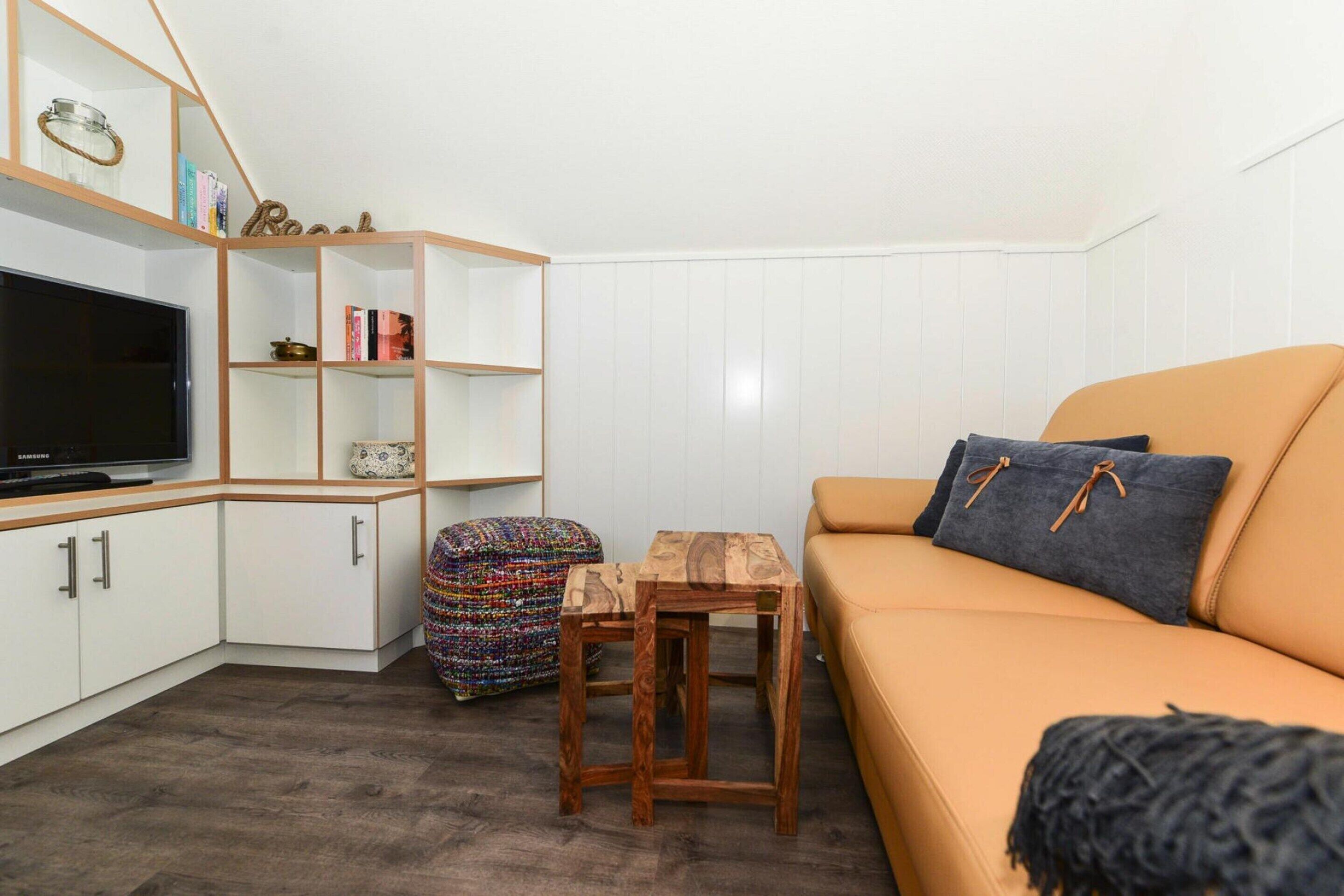 A living room with a sofa, TV, wooden sideboard, and a small table.