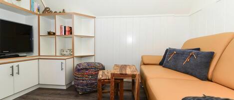 A living room with a sofa, TV, wooden sideboard, and a small table.