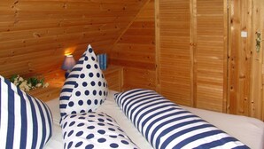 Ein Zimmer mit Holzwänden und einem Bett mit gestreifter und gepunkteter Bettwäsche.