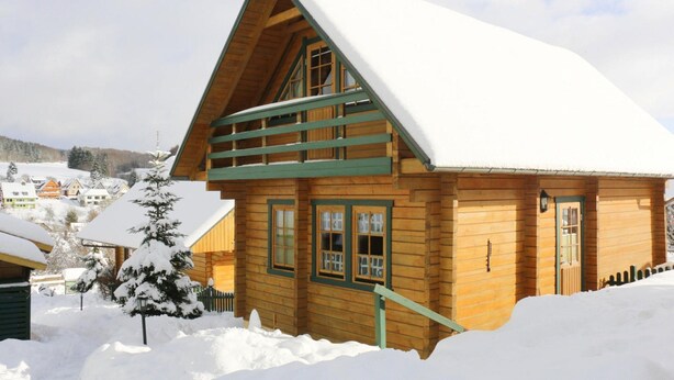 Eine Holzhütte mit einem steilen Satteldach, umgeben von Schnee.