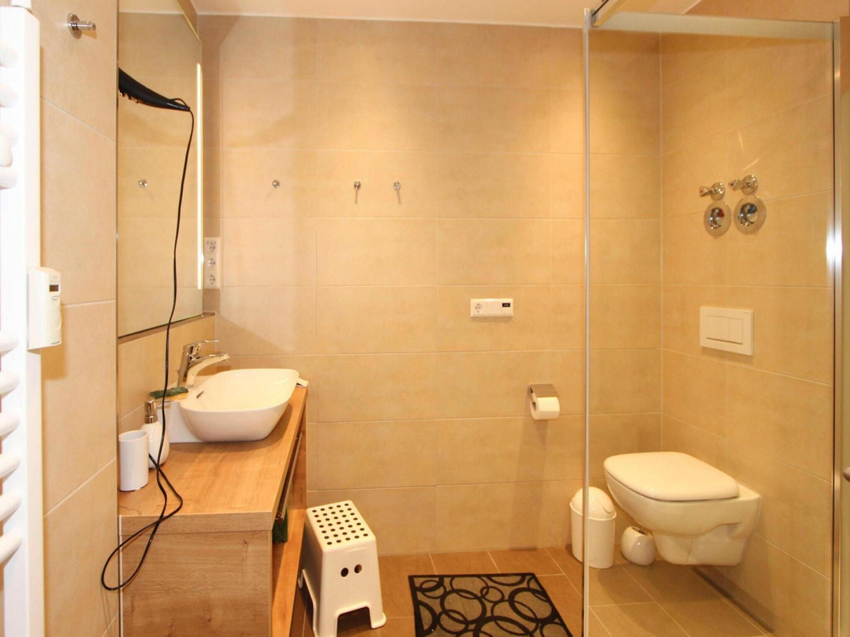 A modern bathroom with a glass shower enclosure, a white sink, and a toilet.