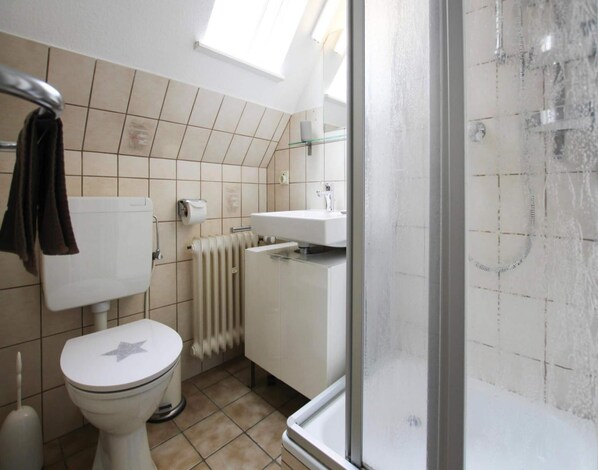 Un baño con inodoro, radiador, lavabo y ducha.