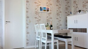 A small dining area with a white table and chairs, a white cabinet, and a door. - Wohnung in Zinnowitz Nahe Meeresstrand (Zinnowitz)