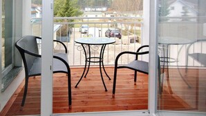 A balcony with a wooden floor, a round table, and four chairs. - Wohnung in Zinnowitz Nahe Meeresstrand (Zinnowitz)