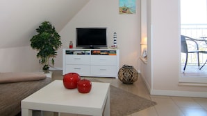 A living room with a flat-screen TV, a plant, and two red apples on a table. - Wohnung in Zinnowitz Nahe Meeresstrand (Zinnowitz)