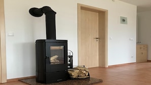 A room with a black wood-burning stove, a door, and a tiled floor.