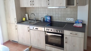 A kitchen with light wood cabinets, a stainless steel sink, a built-in oven, and a dishwasher.