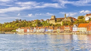 Une ville riveraine qui possède des bâtiments historiques et un château perché sur une colline.