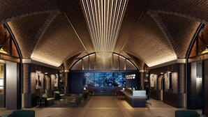 Eine großzügige Lobby mit hoher Decke, einem Empfangsbereich, Sitzbereichen und einem großen Aquarium.