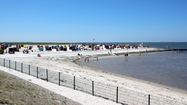 Une plage avec une clôture, des gens et une jetée.