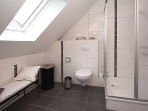 Une petite salle de bain moderne avec un puits de lumière, une douche, des toilettes et un lit.