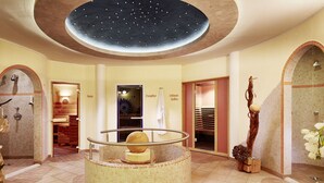 A spacious, well-lit spa area with a circular seating area, a starry ceiling, and a view of a pool. - Maximilian Apartmenthaus 2-6 People (Neukirchen am Grossvenediger)