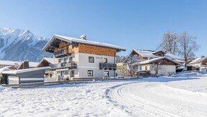 A snow-covered mountain village with modern buildings, including a multi-story structure with a wooden facade and a ski lift visible. - Maximilian Apartmenthaus 2-6 People (Neukirchen am Grossvenediger)