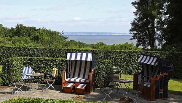 Une terrasse dotée de deux auvents à rayures, d’une table et de chaises.