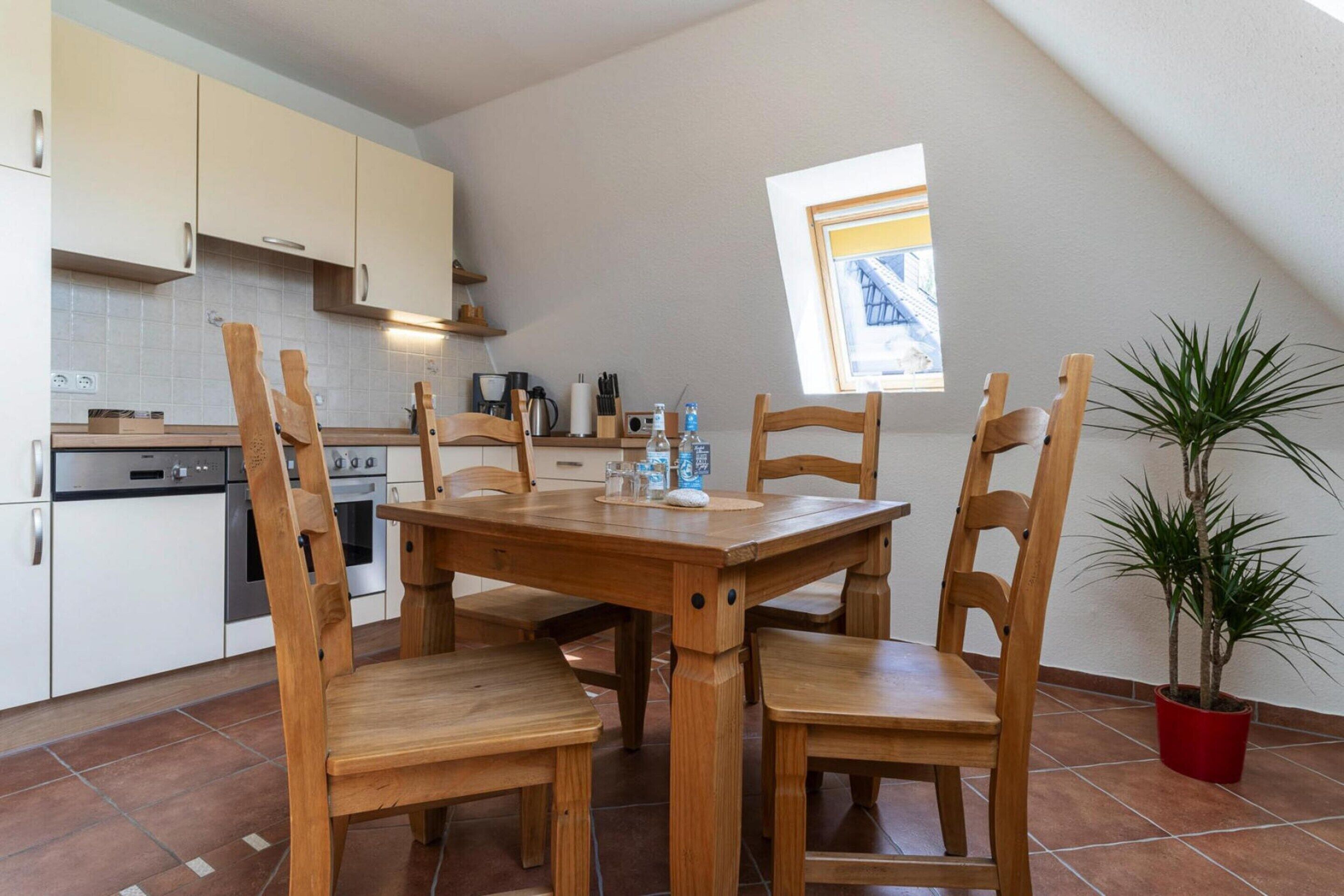 A kitchen with wooden chairs, a dining table, and a potted plant.