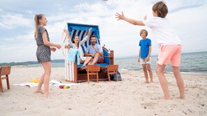 A beach scene with a lounge chair and a person sitting in it. - Appartements im Freizeitpark Weissenhauser Strand (Wangels)