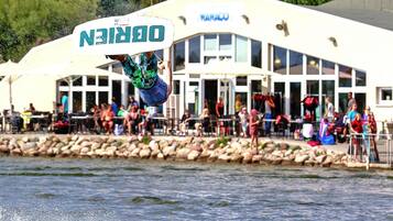 A person performing a trick on a wakeboard in front of a building with a sign that reads "NANO".